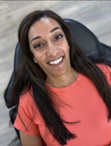 Smiling woman with long dark hair showing microblading brow results